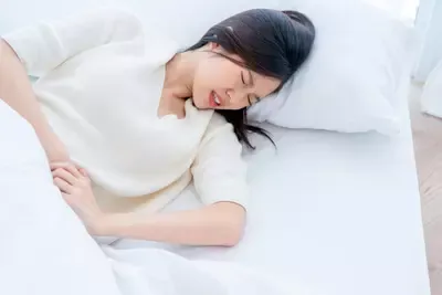 asian-woman-with-menstrual-problems-young-woman-with-stomach-ache-lying-bedlying-bed-holding-her-stomach-(1).webp