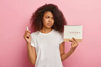 displeased-stressful-dark-skinned-woman-looks-periods-calendar-with-marked-red-crosses.webp